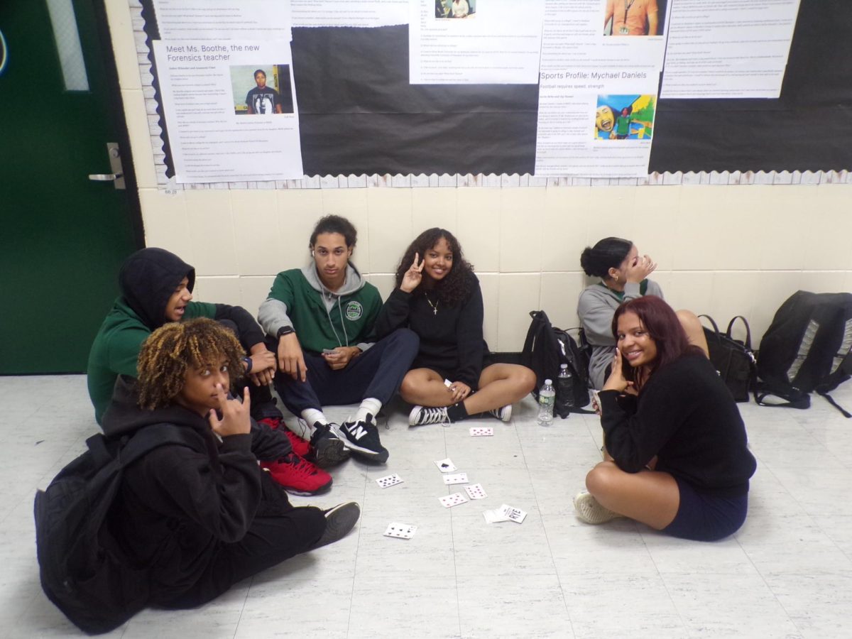 During lunch, some students play card games in the hallway.