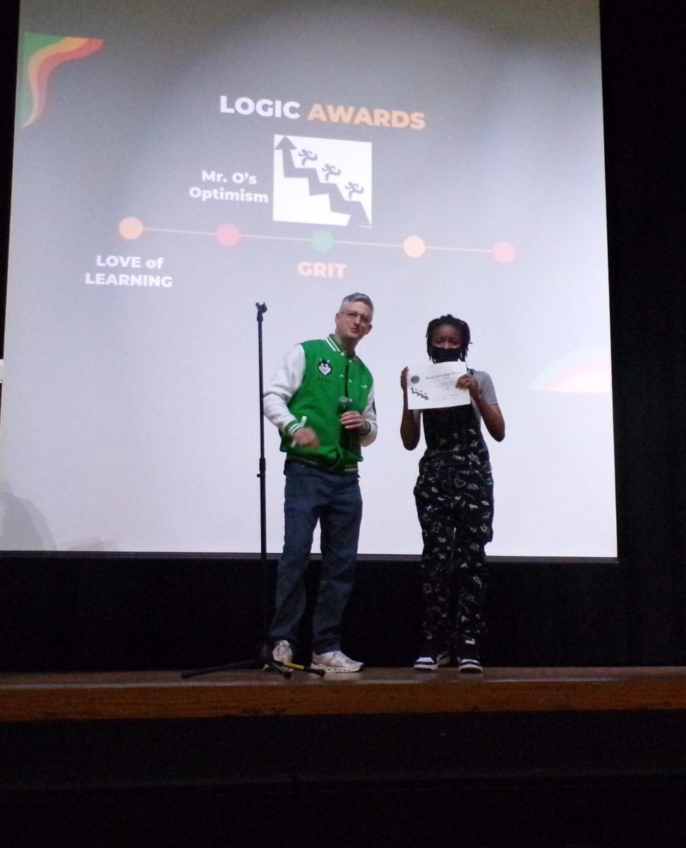 Ninth grade English teacher, Dan Herguth, presents Odell Lowery with Mr. O's Optimism award.