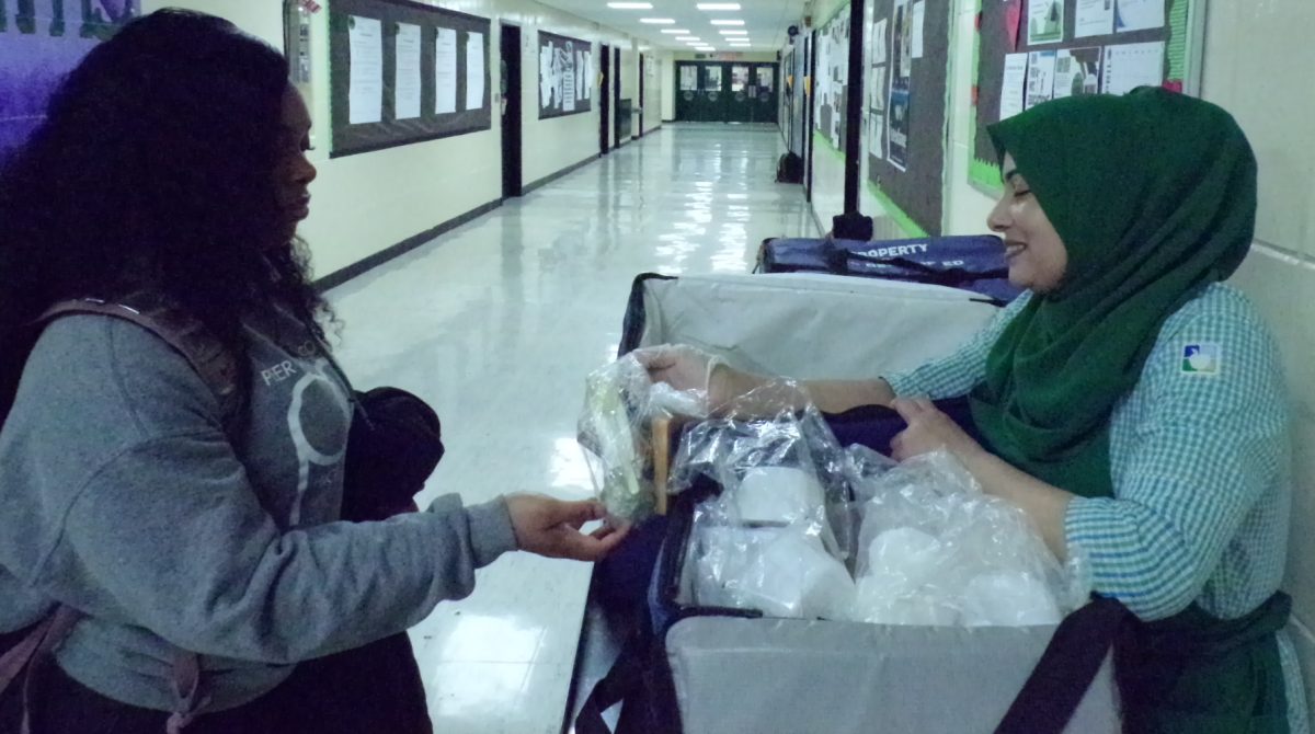 Shahina Chowdhury hands out breakfast each morning in front of the school office. 