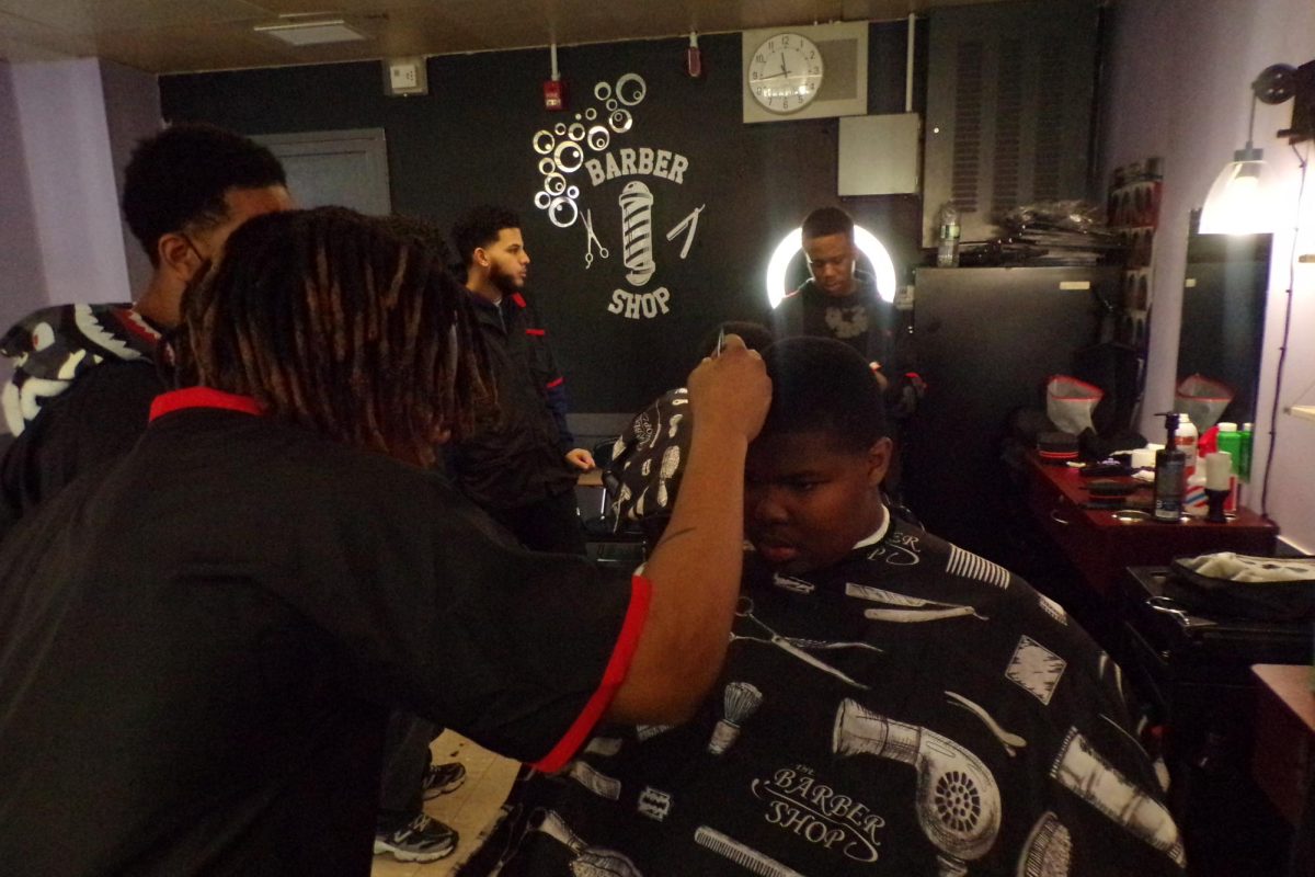 Co-op Tech's barber-in-training, Jalen Martin, works on a freshman's hairline.